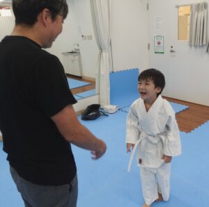 合氣道の稽古場で、親と向き合いながら笑顔を見せる子どもの様子